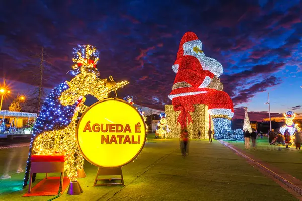Noel Baba ve davul çalan bir şahıs da dahil olmak üzere büyük aydınlatılmış Noel süslemeleri, gece şenlikli bir sahne yaratıyor.