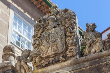 Coimbra 'da tarihi bir binayı süsleyen melek figürleriyle çevrili süslü taş bir arma.