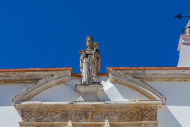 Bakire Meryem 'in bebek İsa' yla birlikte bir heykelinin yakından görüntüsü, karmaşık taş işçiliğiyle bir binanın tepesine tünemiş.