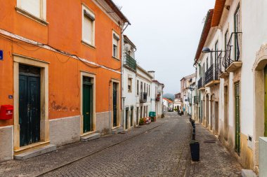 Geleneksel bir Portekiz köyünde renkli evlerle dolu büyüleyici, dar bir cadde.