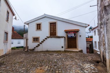 Beyaz yüzlü, kırmızı kiremitli, büyüleyici bir köyün kaldırım taşı sokağında bulunan geleneksel bir Portekiz evi.