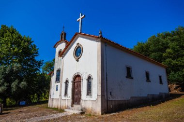 Kırmızı kiremitli, açık mavi gökyüzüne gururla karşı duran, küçük, bembeyaz bir kilise.