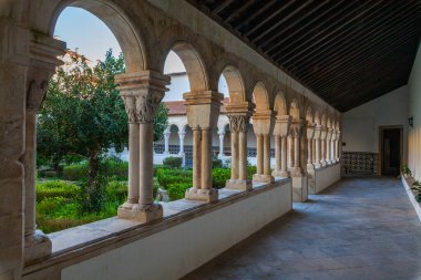 Taş kemerler, sütunlar ve ortasında yemyeşil bir bahçe olan pitoresk bir manastır.