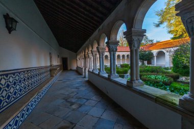 Bir sıra taş sütunları ve kemerleri olan, yemyeşil bahçeye bakan sakin bir manastır. Mavi ve beyaz fayanslar duvarı çiziyor, uzaya biraz renk katıyor.