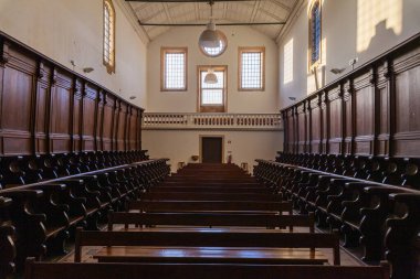 Uzun, yüksek tavanlı ahşap banklarla kaplı tarihi bir kilise ya da manastır.