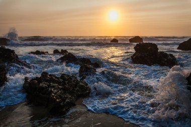 Yumuşak kum, ayak izleriyle işaretlenmiş, ön planda uzanıyor.