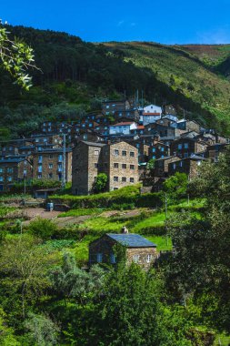 Yeşilliklerin arasına yerleşmiş geleneksel taş evleri olan Portekiz yamaç köyü