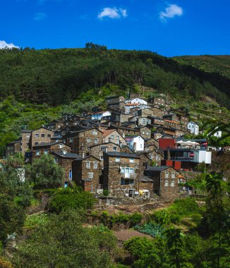 Yeşilliklerin arasına yerleşmiş geleneksel taş evleri olan Portekiz yamaç köyü