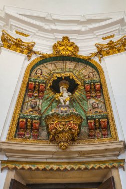 Altın kumaşla kaplanmış bir heykelin merkez heykelini içeren süslü bir sunak. Karmaşık oymalar ve parlak kırmızı ve yeşil detaylarla donatılmış, özenle hazırlanmış bir altın çerçevenin içinde.