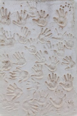 Dokulu bir duvar, insan bağlantısı ve yaratıcılığının dokunsal ve sanatsal bir görüntüsünü oluşturan bir dizi el izi barındırır.