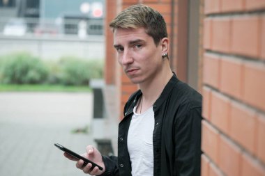 Portrait of a young handsome guy in a black shirt close-up autumn street photography