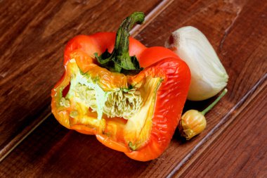 Kırmızı dilimlenmiş şımarık, buruşuk, tatlı biberli, kahverengi bir masaya yakın plan.