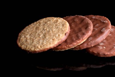 Lezzetli taze yulaf ezmeli kurabiyeler ve siyah ayna arka planında çikolatalı krema.