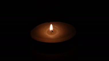 A candle is lit with a burning match on a black background close-up video 4k