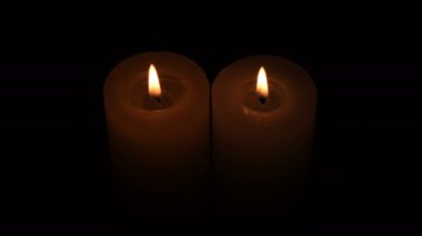 A candle is lit with a burning match on a black background close-up video 4k