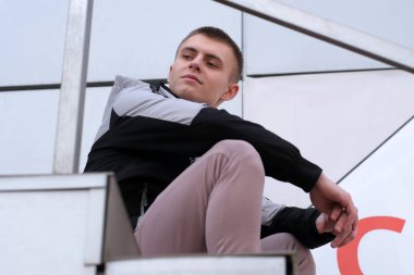 Bahar şehrinin caddesinde kısa saçlı yakışıklı bir adamın portresi merdivenlerin basamaklarında oturuyor.