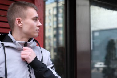 Bahar şehrinin caddesinde, dükkanın cam vitrininin yanında kısa saçlı yakışıklı bir adamın portresi.