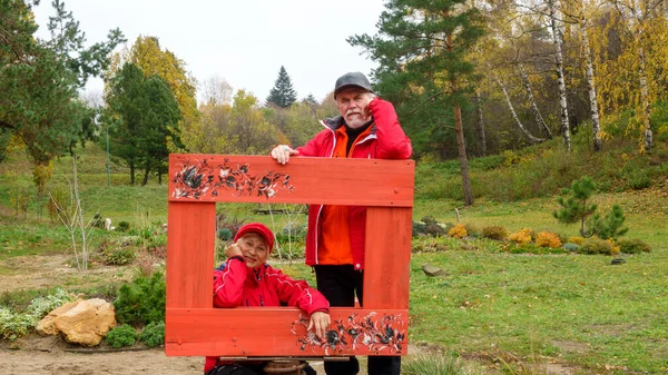 高齢者白髪楽観的なカップルで愛男と女で風景公園で秋に赤防風林 — ストック写真