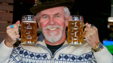 Yaşlı, gri saçlı, sakallı yakışıklı bir adam bira barında dinleniyor.