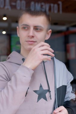 Genç ve yakışıklı bir adam yol kenarındaki bir kafede kahve içiyor. Pencere camından.