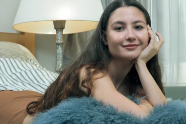 Portrait of a young beautiful girl with long wavy hair in light brown lingerie