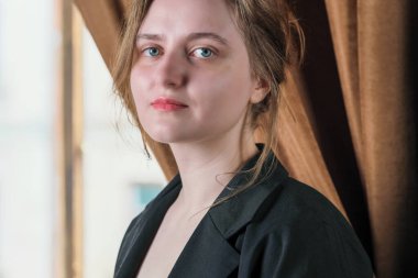 Kahverengi arka planda siyah elbiseli, kahverengi saçlı, çekici bir kızın portresi.