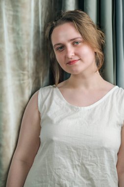 Beyaz tişörtlü çekici bir kızın portresi. Arka planda açık renk.