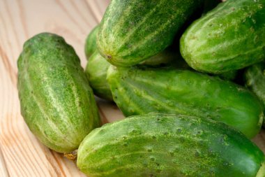 Hafif ahşap zemin üzerinde ev yapımı yıkanmamış salatalıklar, yakın plan, sebze kompozisyonu.