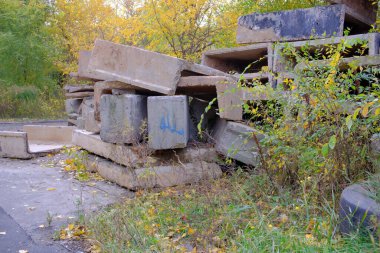 Büyük inşaat döküntüleri, beton döküntüler ve bloklar şehir sınırlarında uzanıyor ve sonbahar bulutlu bir günde çevreyi kirletiyor.