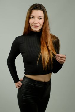 Stüdyoda poz veren siyah pantolonlu, uzun kızıl saçlı güzel bir kızın portresi.