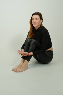 Stüdyoda poz veren siyah pantolonlu, uzun kızıl saçlı güzel bir kızın portresi.