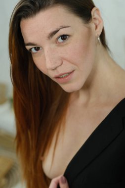 Siyah ceketli, uzun kızıl saçlı güzel bir kızın portresi stüdyoda yakın plan fotoğrafı.