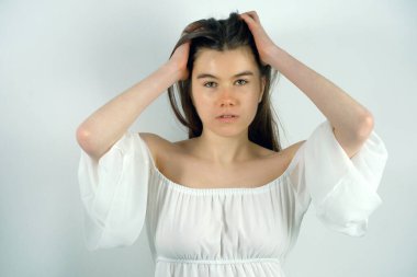 Beyaz açık renk elbiseli, arka planda poz veren oldukça uzun boylu bir genç kız..