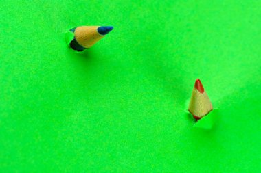 Küçük kırmızı ve mavi kalemler yeşil kağıt kırıntıları, soyut kavramsal arkaplan, makro