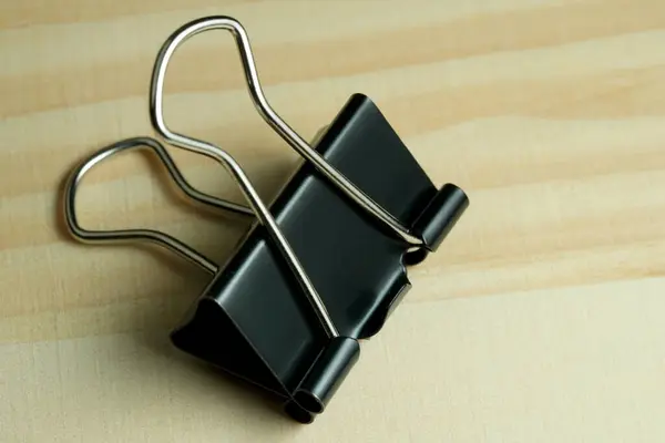 Stationery binder clip on a wooden table, close-up