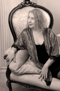 Yaşlı, güzel, sarışın, kırmızı cüppeli kıvırcık bir kadın stüdyoda poz veriyor..