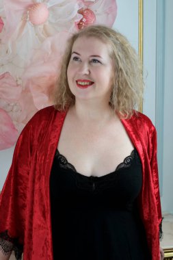 Yaşlı, güzel, sarışın, kırmızı cüppeli kıvırcık bir kadın stüdyoda poz veriyor..