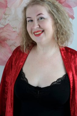 Yaşlı, güzel, sarışın, kırmızı cüppeli kıvırcık bir kadın stüdyoda poz veriyor..