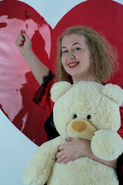 Yaşlı, güzel, sarışın, kırmızı cüppeli kıvırcık bir kadın stüdyoda poz veriyor..