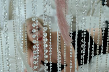 İç çamaşırlı, yaşlı, sarışın, kıvırcık bir kadın stüdyoda bir yatakta poz veriyor..