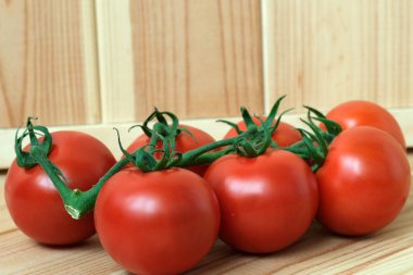 Kırsal ahşap bir masada düzgünce dizilmiş birkaç olgun domates..