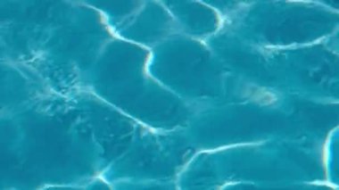 Güneşli bir günde havuzda su dalgalanmalarının yakın çekim görüntüleri.
