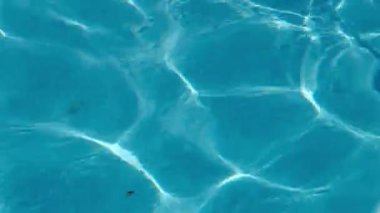 Dalgalar ve güneş ışığı yansımalarıyla mavi havuz suyu