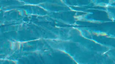 Güneşli bir günde havuzda dalgalanan suyun yakın görüntüsü.