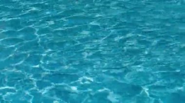 Berrak, mavi havuz suyu güneşte hafifçe dalgalanır.