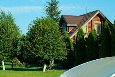 Yeşil ağaçlar ve çimlerle çevrili ahşap bir kulübe..