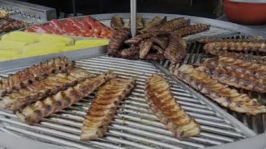 Etler, hareketli bir etkinlikte canlı sebzelerin yanında ızgarada cızırdar..