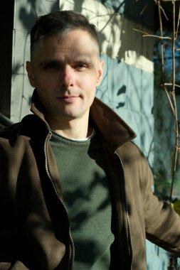 Kendine güveni olan bir adam, büyüleyici doğal ışıkla dışarıda poz verir ve özelliklerini ön plana çıkarır..