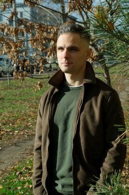 Gün ışığında sakince duran bir adam, kendini sonbaharın güzelliğine daldırır..