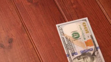 Yeni temiz 100 $'lık banknotlar siyah ahşap bir masanın üzerine serildi.